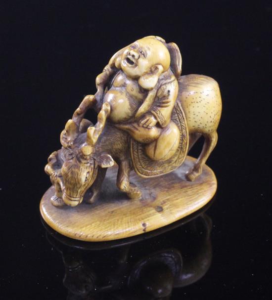 A Japanese stained ivory okimono netsuke of Hotei riding a deer, signed Tomochika, Meiji period, 4.1cm